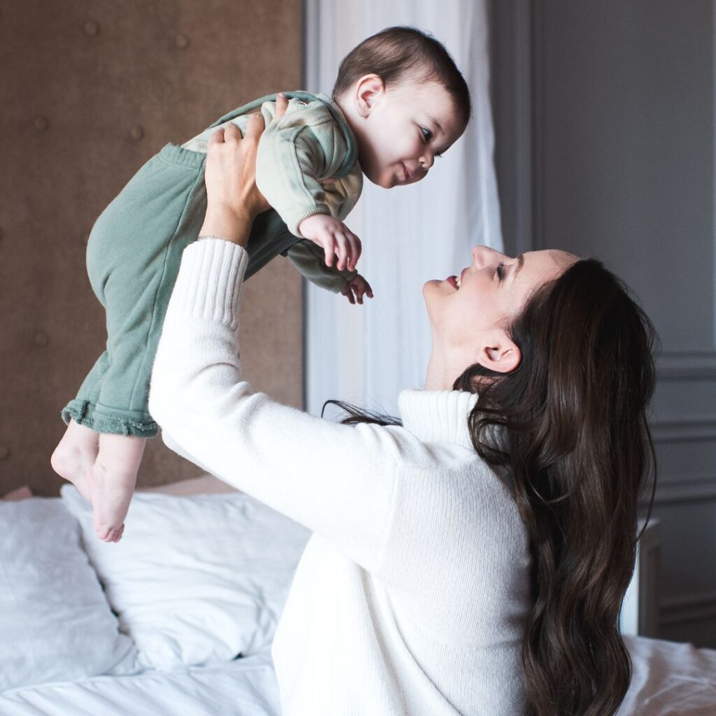 Mãe a brincar com o filho na cama, sem dor